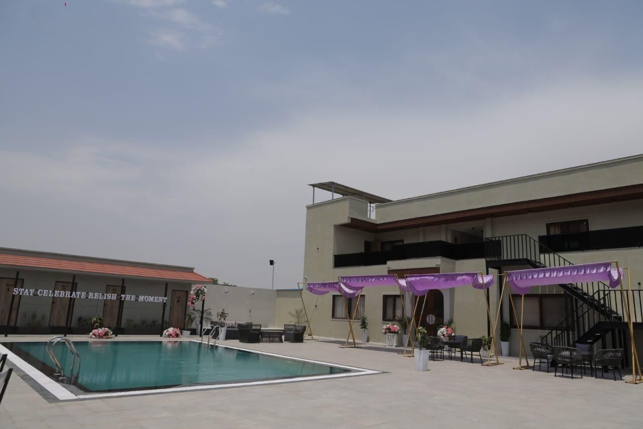 A swimming pool area with a building in the background, a staircase, and outdoor seating.