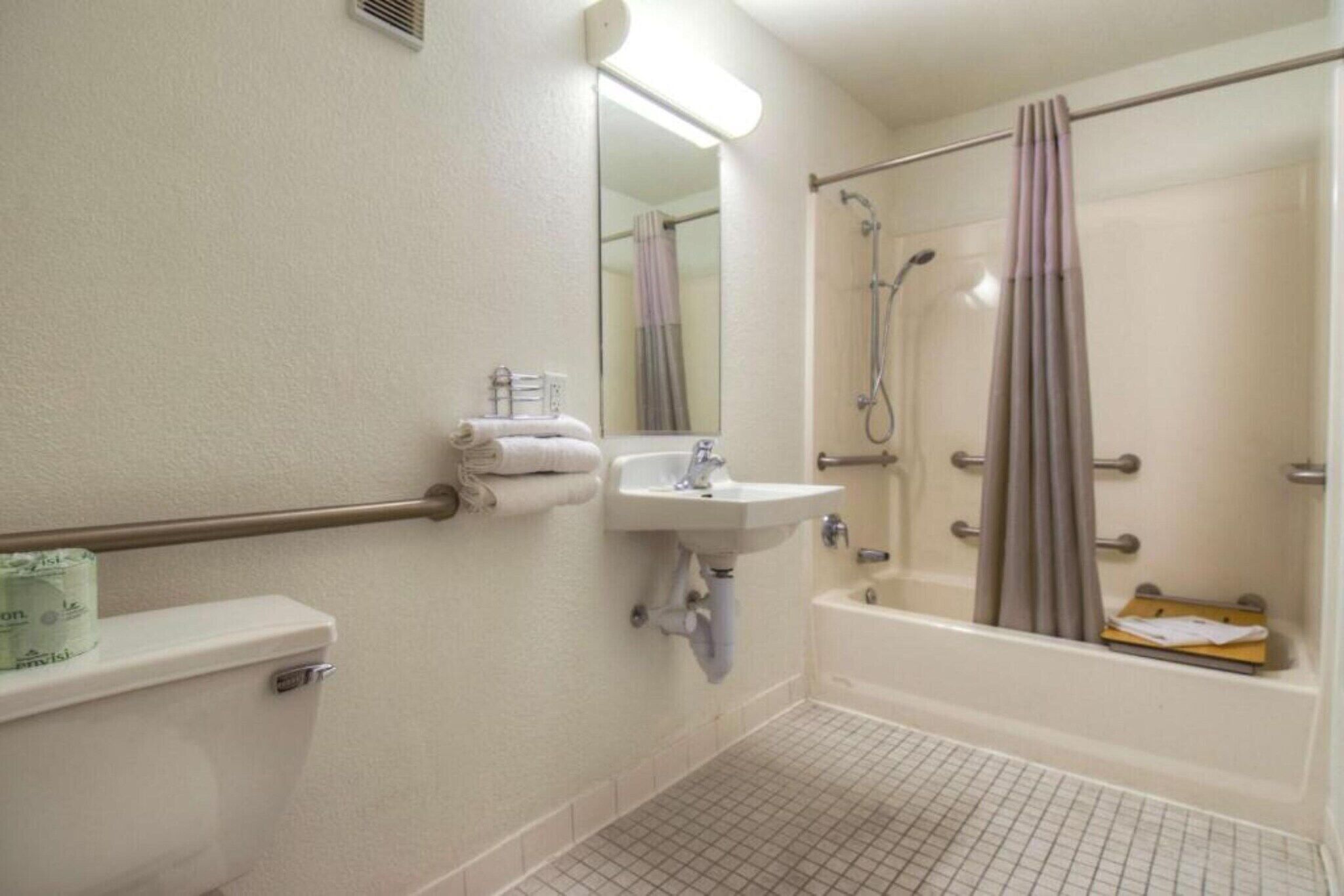 Un baño de hotel estándar con inodoro, lavabo y zona de ducha.