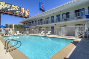 A hotel with a swimming pool, lounge chairs, and a sign advertising a Rat Pack event. - 2 Full Beds | Non-Smoking (Las Vegas NV)