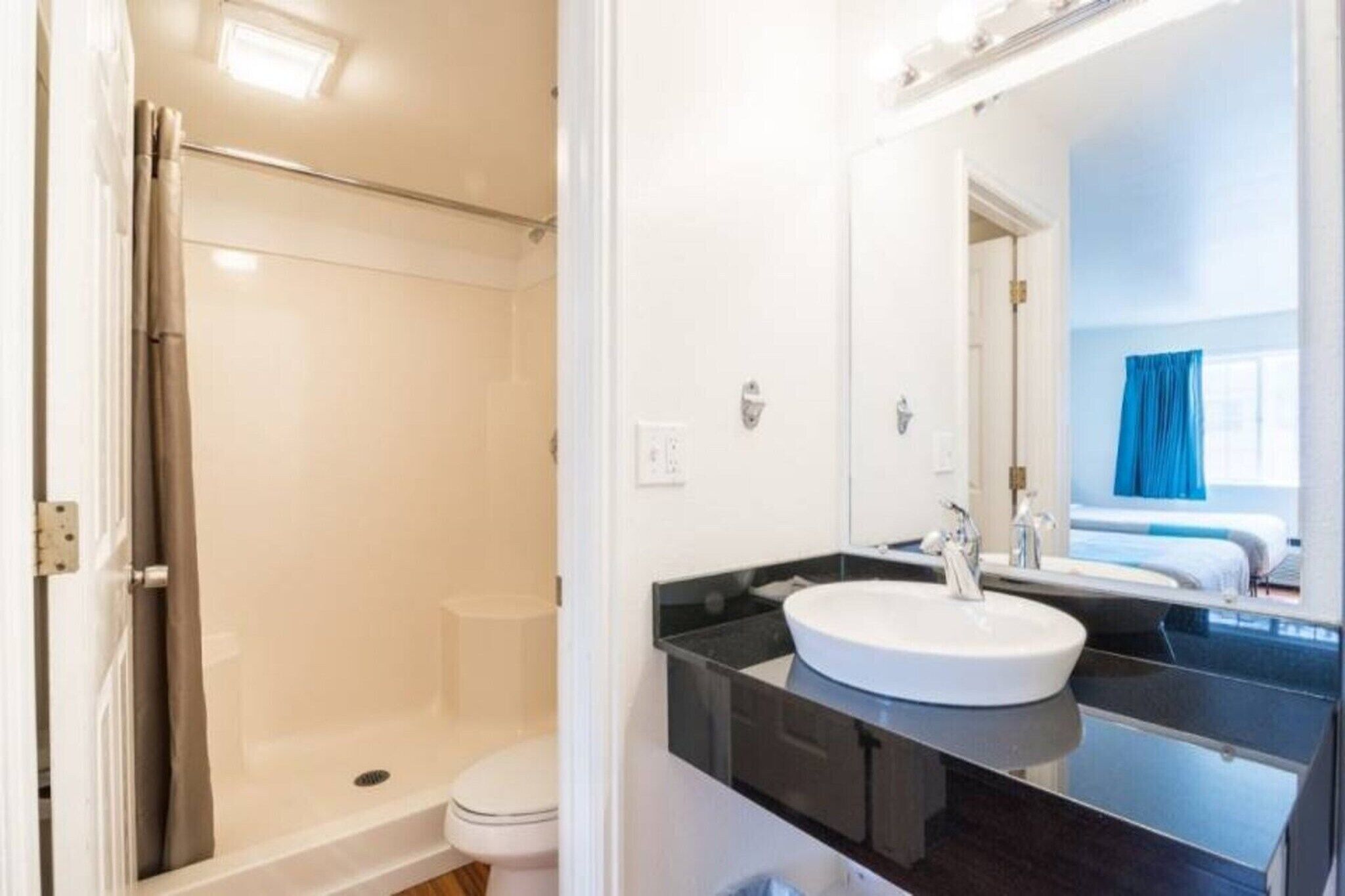 A bathroom with a shower, toilet, and a sink with a mirror.