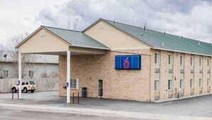 Un motel doté d’un parking couvert, d’un panneau indiquant qu’il est accessible aux personnes handicapées et d’un panneau avec le chiffre « 6 » indiquant le nombre de chambres.