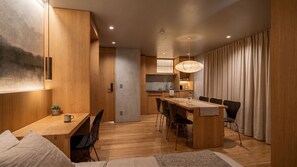 Una cucina moderna con mobili in legno, un'area pranzo con tavolo e sedie in legno, e un'ampia finestra con tende.