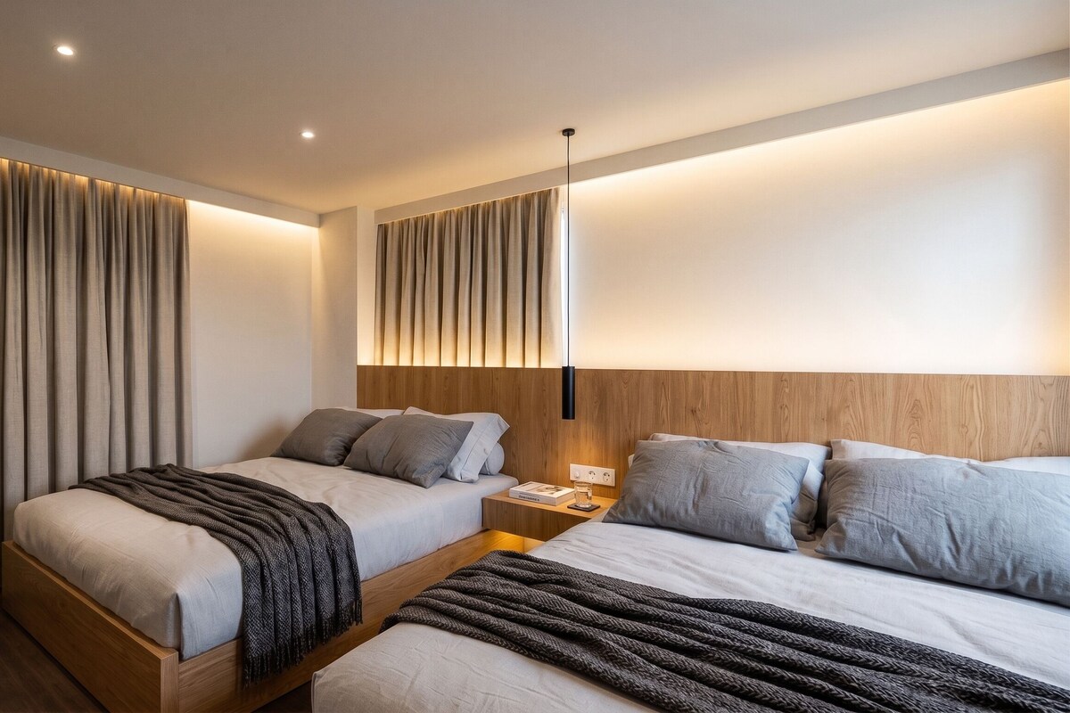 Una moderna camera d'albergo con due letti, una testiera in legno, un comodino e una lampada a parete.