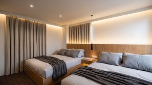 Una moderna camera d'albergo con due letti, una testiera in legno, un comodino e una lampada a parete.