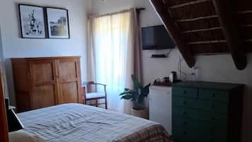 A bedroom with a bed, a wooden cabinet, a television, and a window with curtains.