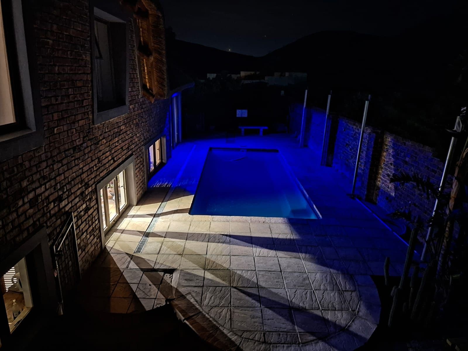 Un área de piscina con suelo de baldosas y pared de ladrillo.