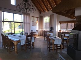 Comedor con una mesa grande y sillas, zona de cocina con estufa y vistas al exterior.