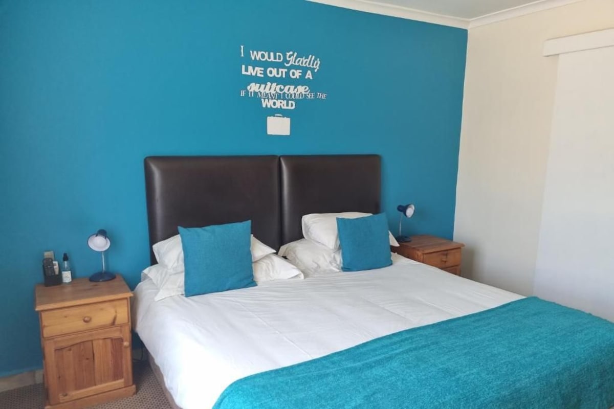 Un dormitorio con cama, mesita de noche, un reloj de pared y una frase motivadora en la pared.