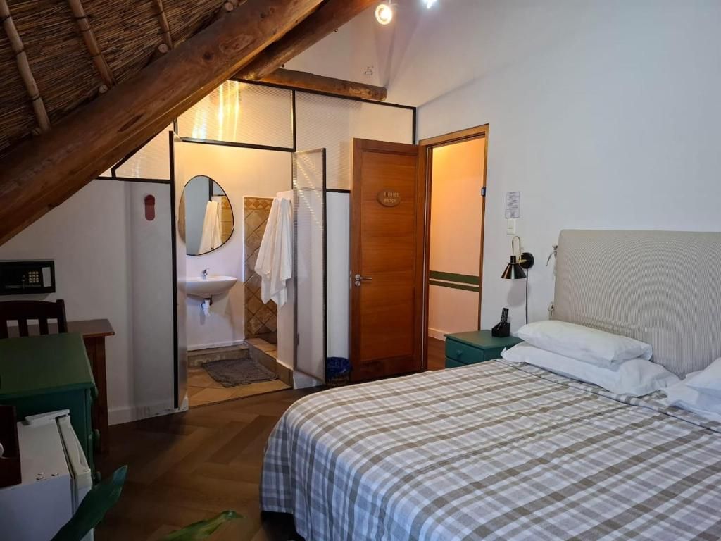 A bedroom with a bed, a bedside table, a nightstand, a mirror, a door, and a small table with a chair.