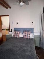 Un dormitorio con cama, ventilador de techo, mesita de noche y cómoda.