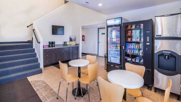 Una hall d'albergo con una scala, angolo cottura, distributori automatici e zona salotto.