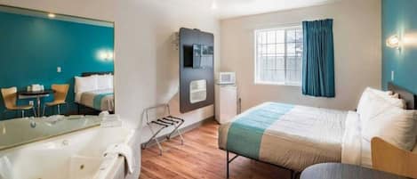 Una camera d'albergo moderna con un letto grande, un'area salotto separata, una vasca e una finestra con tende.
