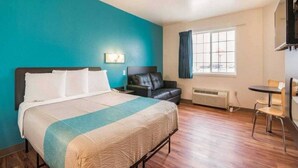 Una camera d'albergo con un letto, una scrivania, una sedia, un divano e una finestra con tende.