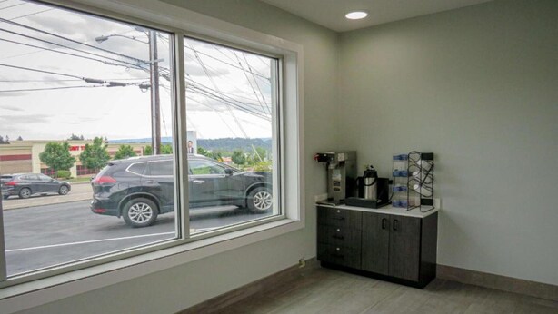 Una habitación con un ventanal grande, un mueble con enchufes y vista a un estacionamiento.