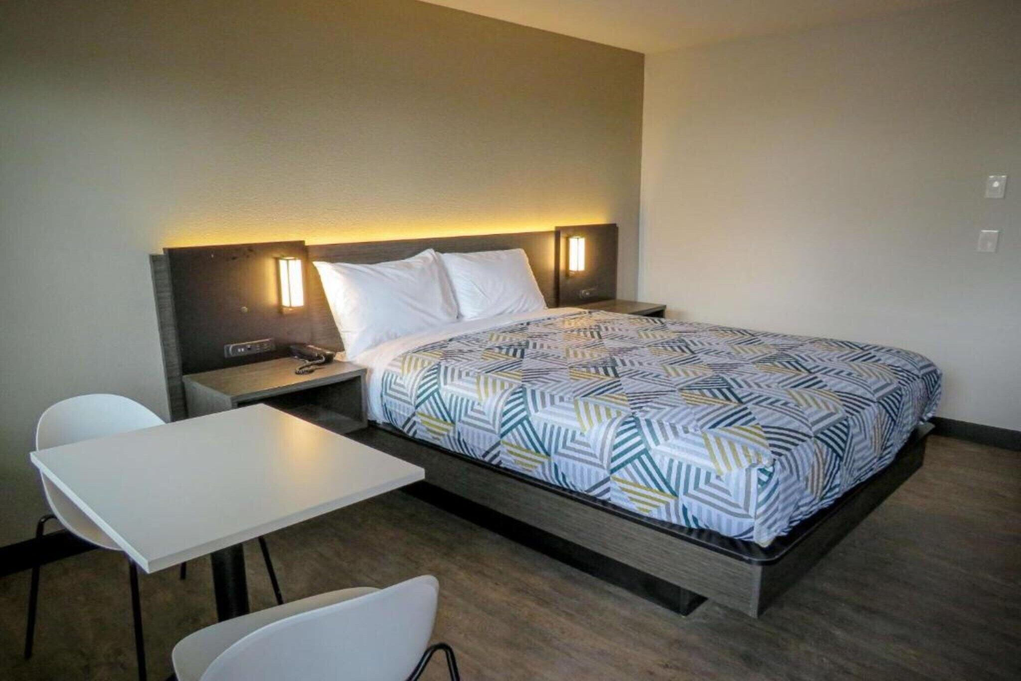 Une chambre d’hôtel avec un lit, des tables de chevet, un bureau et une chaise.