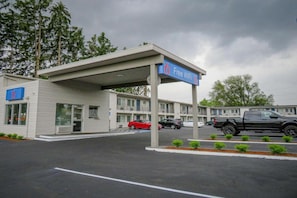 Et motel med et overdækket parkeringsområde, et tydeligt skilt der viser gratis WiFi, og en bygning med et skilt med nummer 6.
