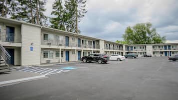 A motel with multiple-story buildings, a parking lot with marked handicapped spaces, and a few cars parked.