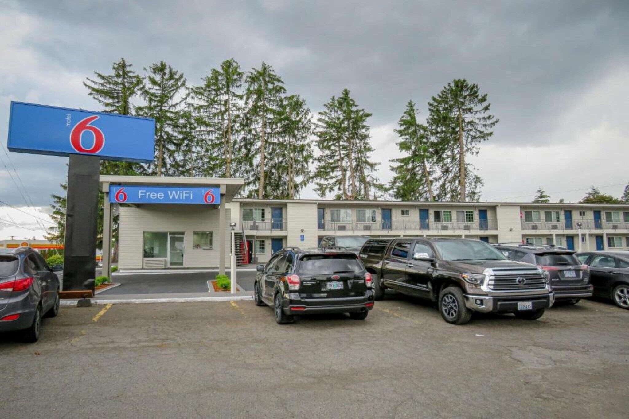A motel with a sign indicating free WiFi, a parking lot with several cars, and a row of motel rooms in the background.