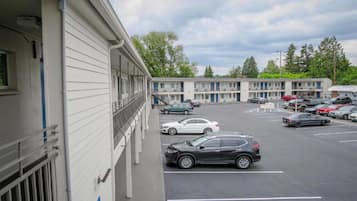 A motel with a parking lot, multiple cars parked, and a building with a balcony.