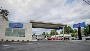 Ein Motel mit großem Parkplatz, überdachtem Parkbereich und einem Gebäude mit der Aufschrift '6'.