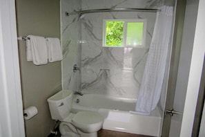 Un baño con inodoro, bañera y zona de ducha.