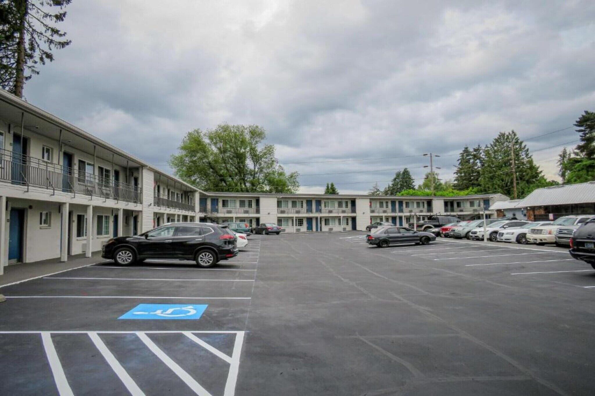 A motel with a parking lot, including a handicapped parking space.