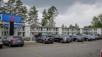 Un motel con aparcamiento, varios coches y un cartel que indica acceso a WiFi.