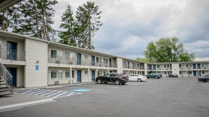 Un motel con varios pisos, espacios de estacionamiento y cielo despejado.
