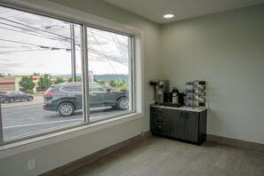 A room with a large window, a cabinet with electrical outlets, and a view of a parking lot. - 1 Queen Bed | Non-Smoking (Tigard)