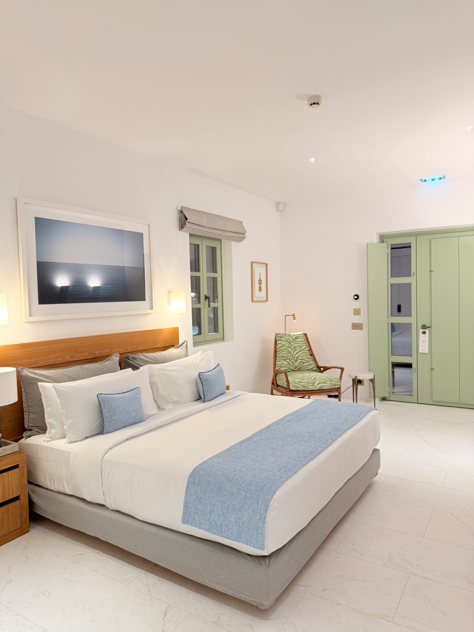A neatly arranged bedroom with a bed, bedside tables, a chair, and a wardrobe.