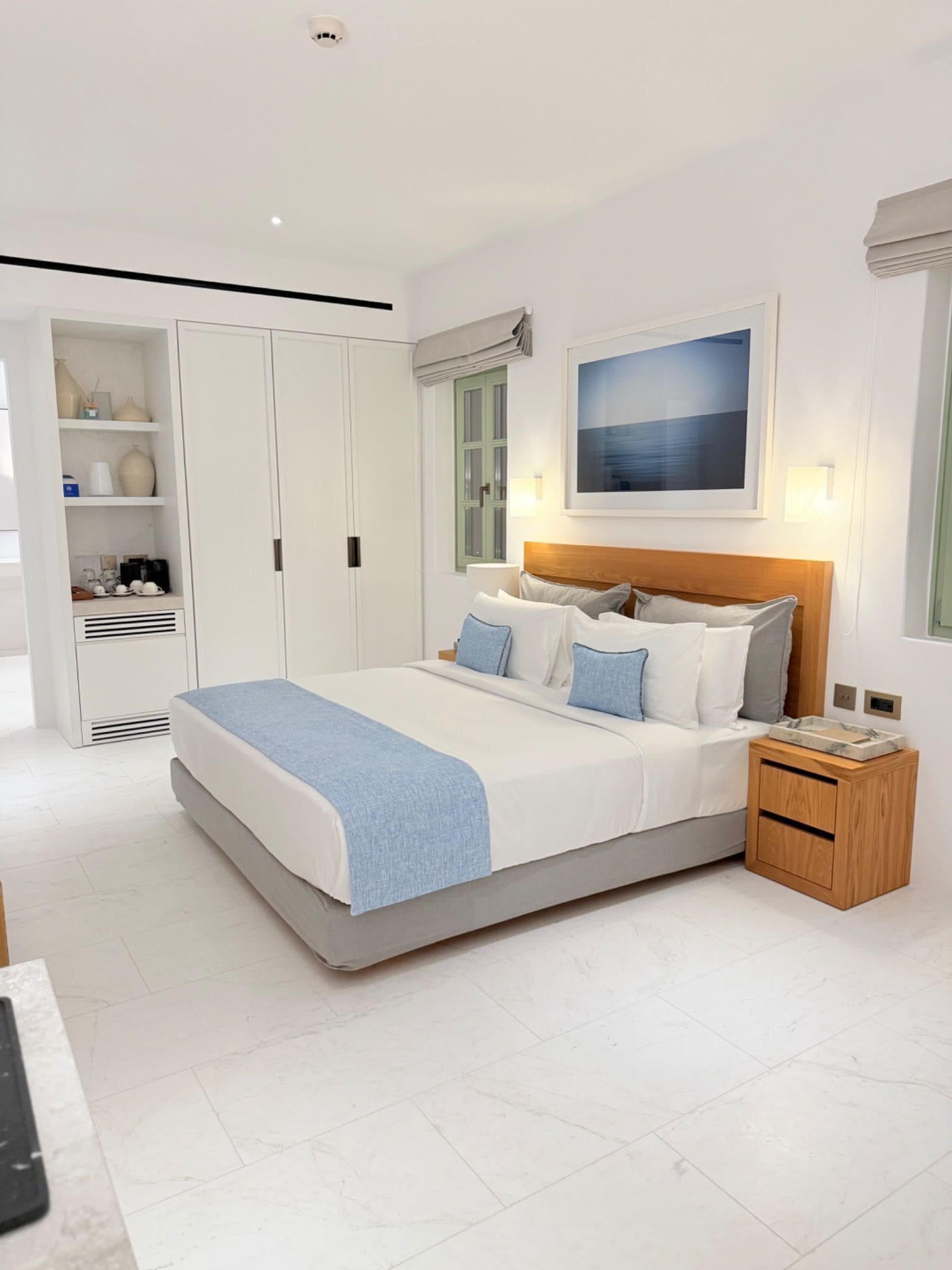 A modern bedroom with a large bed, bedside tables, a wardrobe, and a painting on the wall.