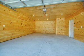 A spacious room with wooden walls and a concrete floor, featuring a door and a ceiling-mounted light fixture. - 7 Mi to Lucas Oil Speedway! Home w/ Patio & Yard (Wheatland)