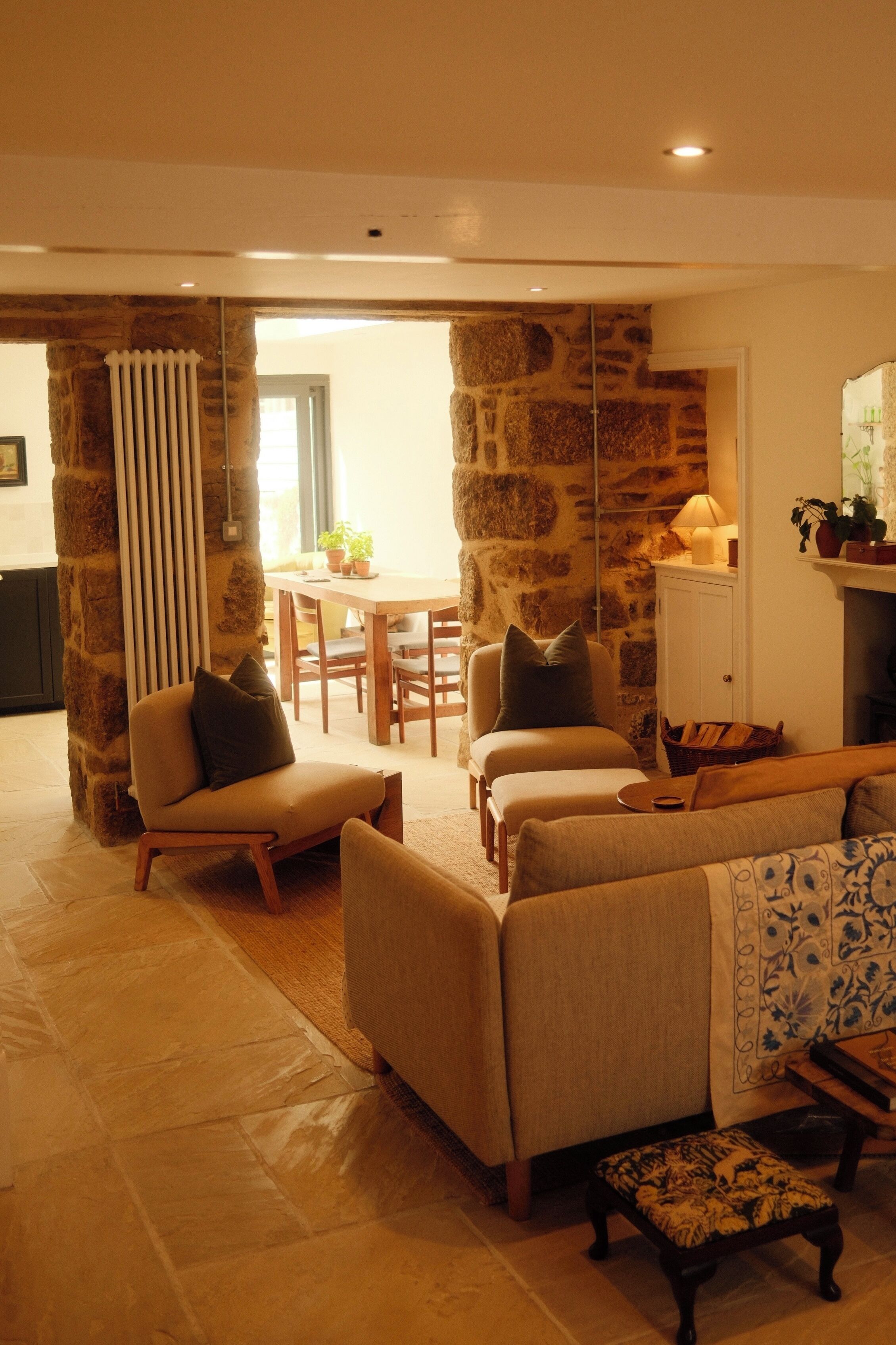A living room with a stone wall, a sofa, a coffee table, and a dining area with a table and chairs.