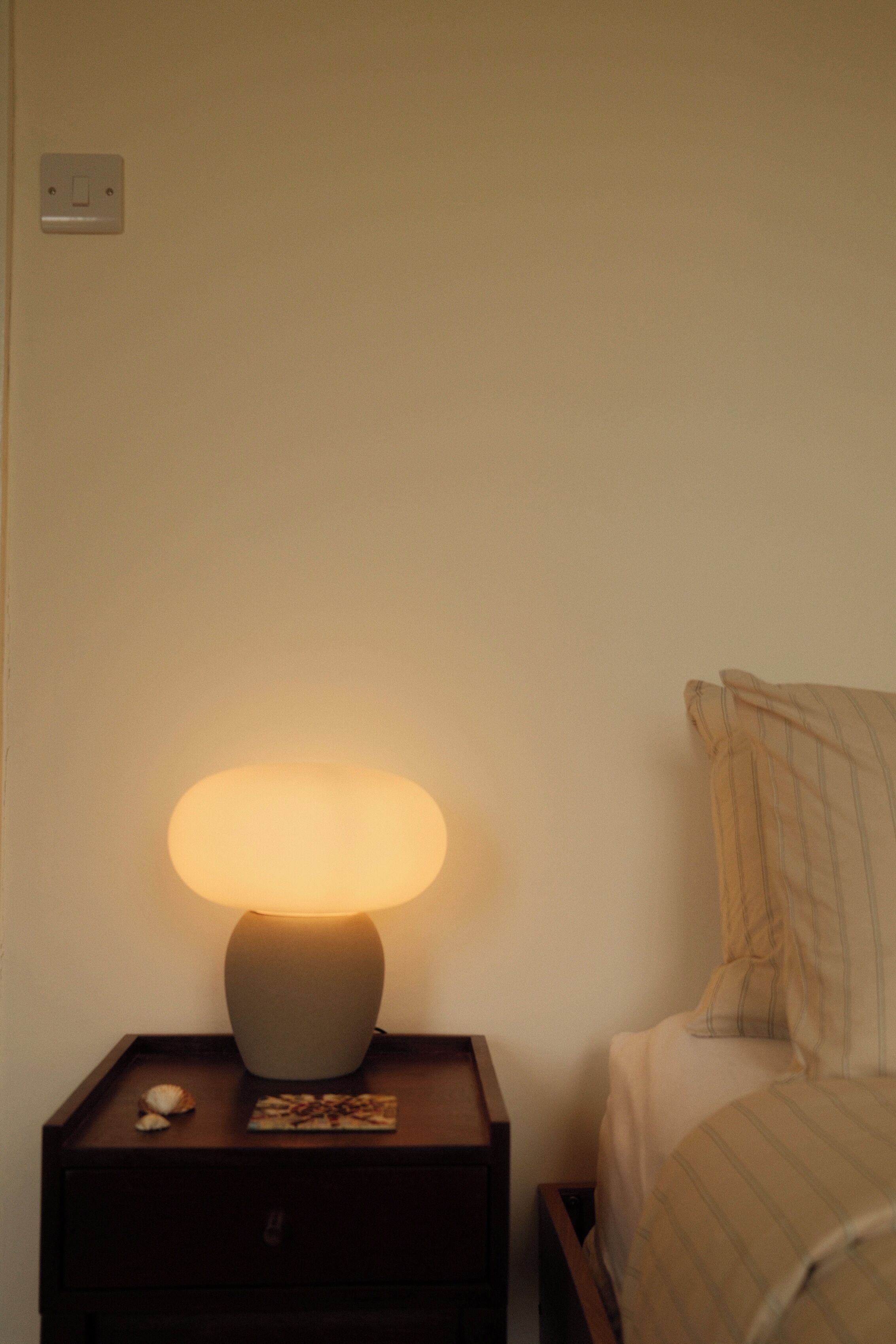 Ein Nachttisch mit Lampe, einer kleinen Dekoration und einem Buch.