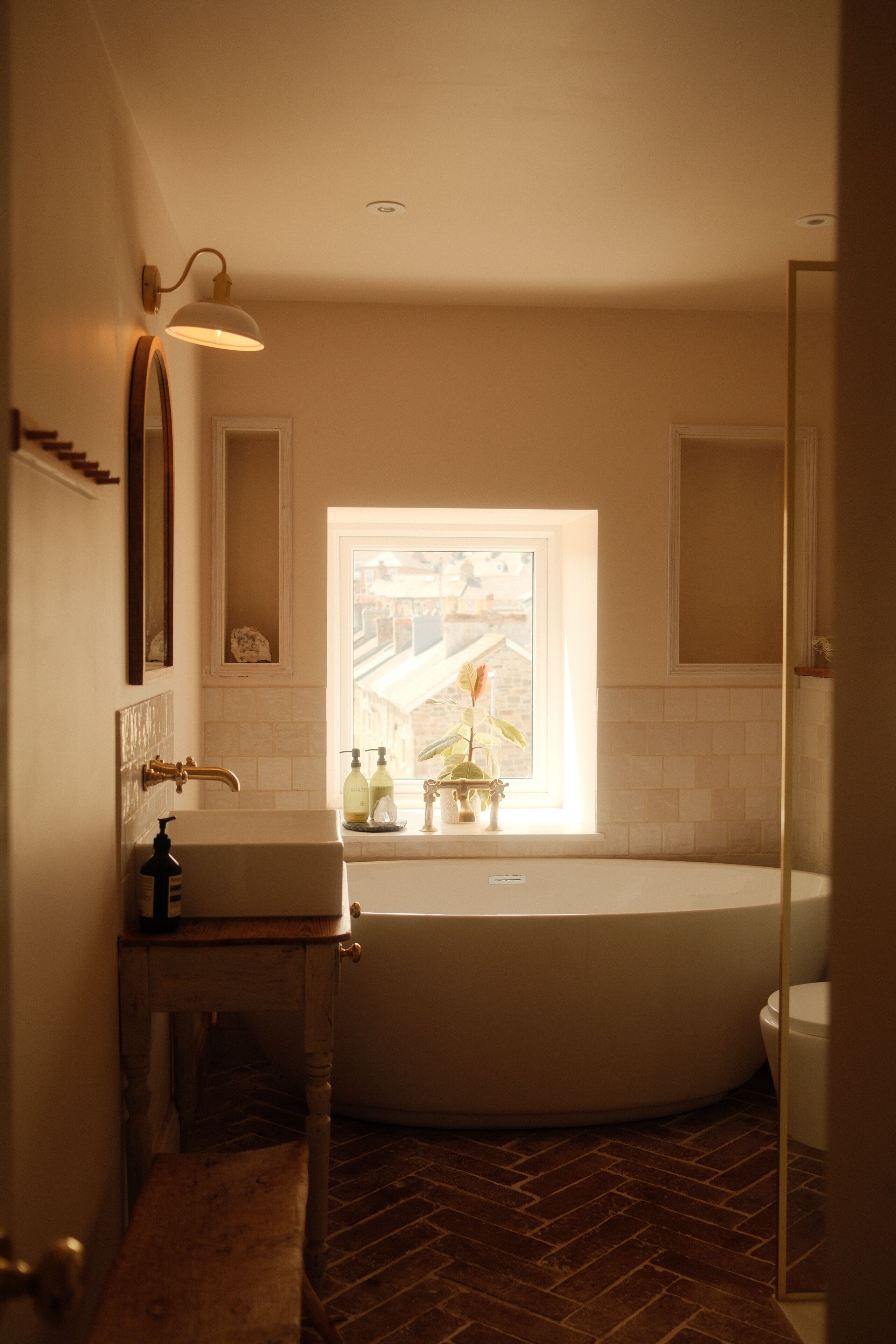 A bathroom with a freestanding bathtub, a sink with a mirror, and a window providing a view of the outside.