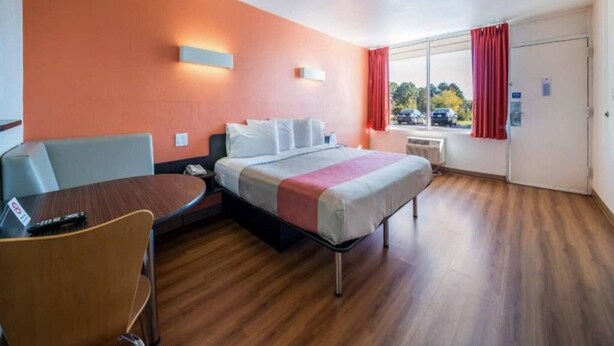 A hotel room with a bed, a desk, a chair, and a window with curtains. - Spacious King Bed|Free Wifi&Parking (CONNELLY SPRINGS)