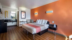 Een hotelkamer met een bed, nachtkastje en een bureau met stoel.