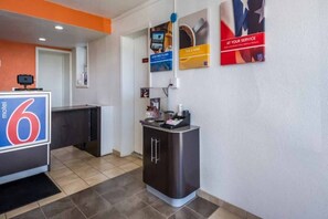 Un vestíbulo de hotel con una recepción, una kitchenette y un pequeño mostrador con una cafetera.