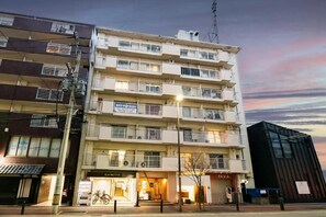 Un edificio de varios pisos con balcones, una bicicleta estacionada afuera y un escaparate visible.