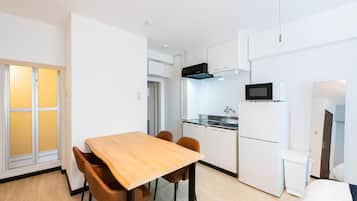 Una cocina compacta con armarios blancos, un microondas y un refrigerador.