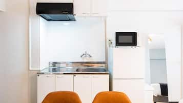 A compact kitchen with white cabinets, a black microwave, and a stainless steel sink.
