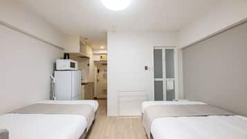 Une chambre d’hôtel avec deux lits, une kitchenette et une salle de bain.