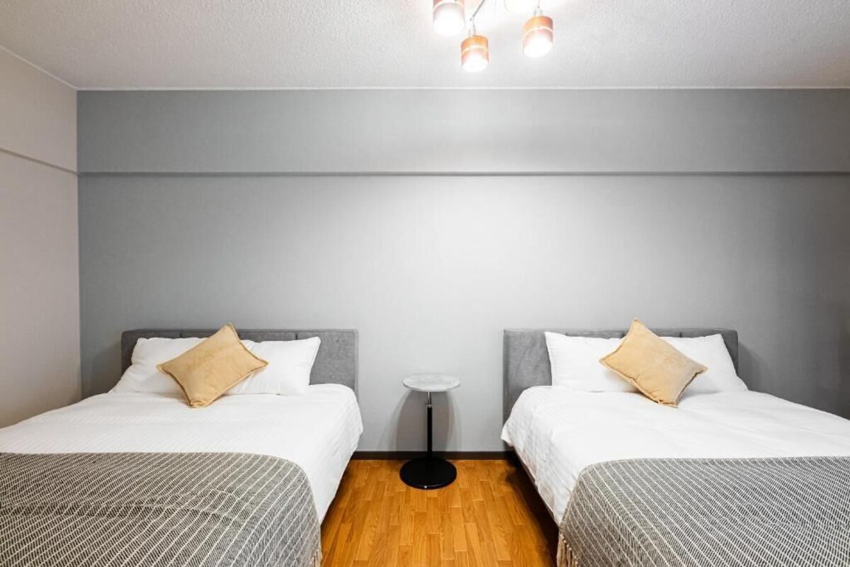 A hotel room with two beds, a small round table, and a ceiling light fixture.