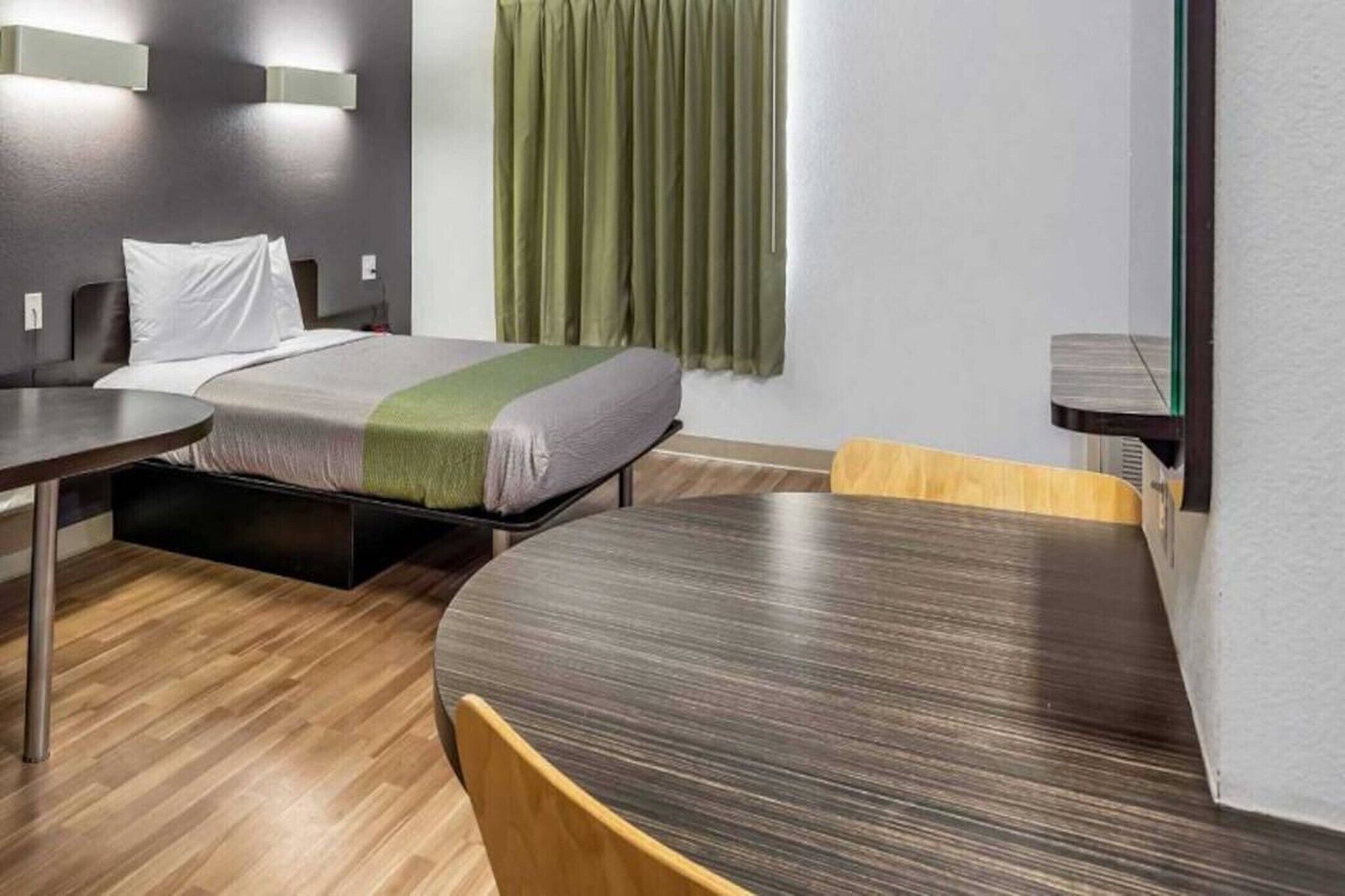 Una habitación de hotel con una cama, un escritorio, una silla y un espejo.