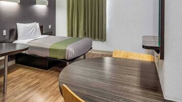 Una habitación de hotel con una cama, un escritorio, una silla y un espejo.