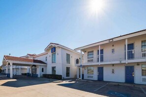 Une rangée de bâtiments d’un motel à deux étages, avec un parking devant.