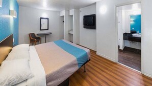 Ein Hotelzimmer mit einem Bett, einem Schreibtisch, einem Stuhl, einem Fernseher und einem Badezimmer.