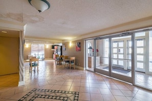 A spacious living area with a tiled floor, a dining table with chairs, and a large sliding glass door leading to an outdoor area. - 1 King Bed | Non-Smoking (Grand Prairie)