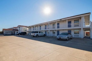 A motel with multiple rooms, a parking lot, and a clear sky. - 1 King Bed | Non-Smoking (Grand Prairie)