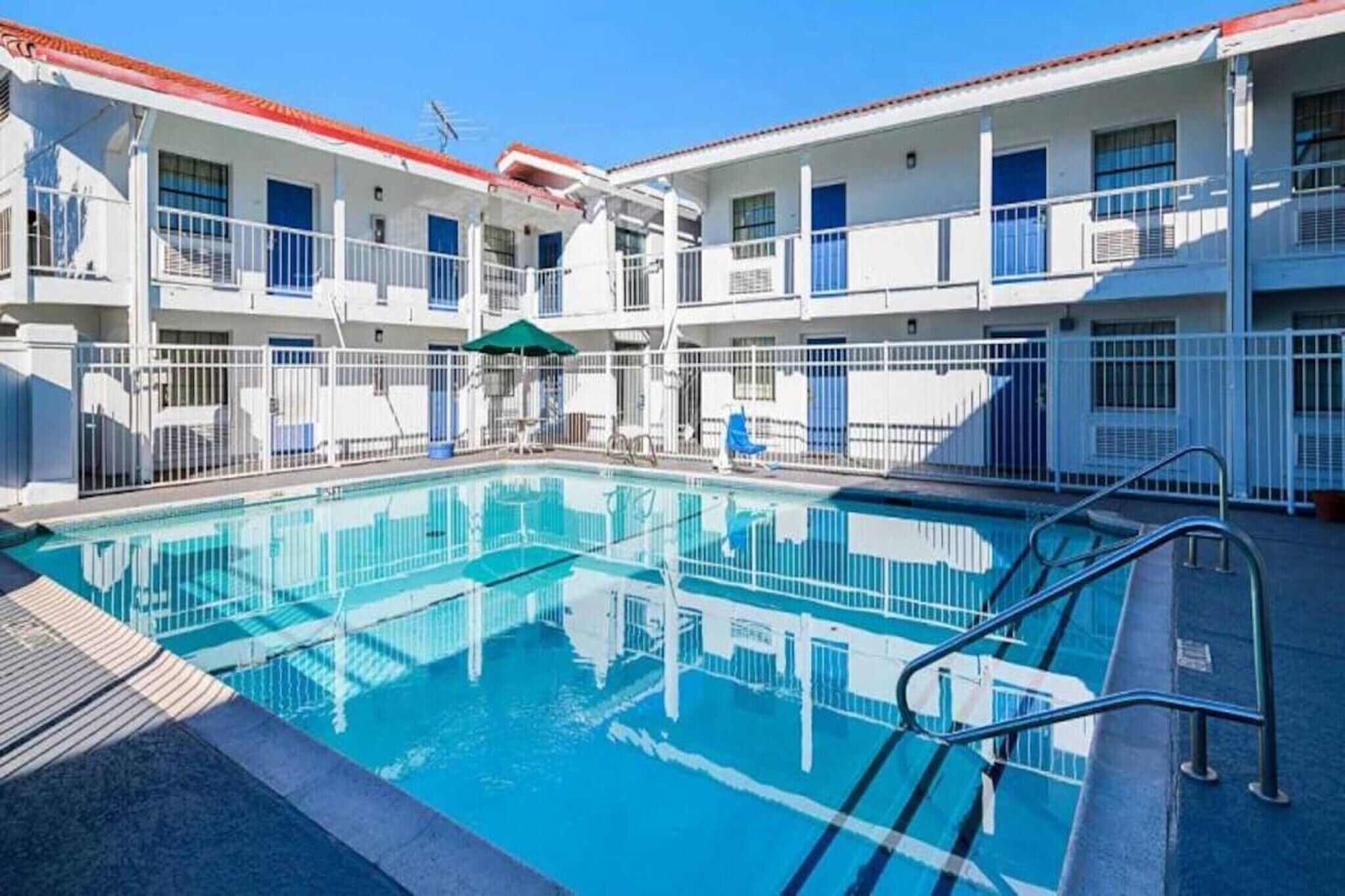 A hotel with a swimming pool, multiple balconies, and a red-tiled roof.